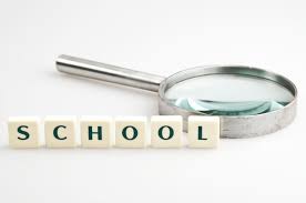 Image of the word School written out in tiles with an adjacent magnifying glass.